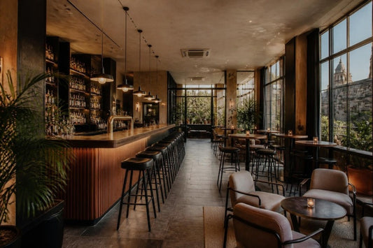 Bar moderno con barra de madera, bancos altos, mesas periqueras y sillones lounge – mobiliario para bar en Guadalajara